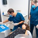 Dental clinic, dentist and assistant performing a 3d scan of the lying patient