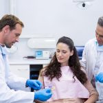 Dentist showing model teeth to patient in dental clinic